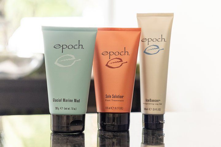 Drei Pflegeprodukte der NU SKIN Epoch-Linie auf einer Glasfläche