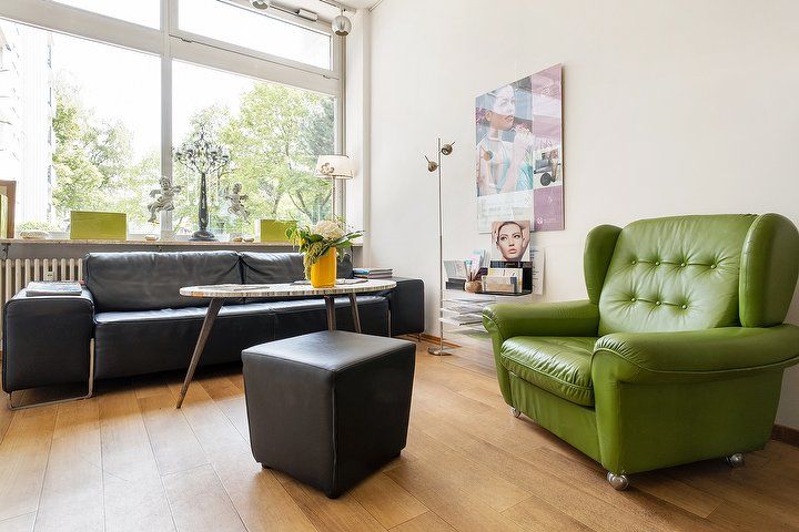 Wartebereich mit Sofa, Sessel und großen Fenstern